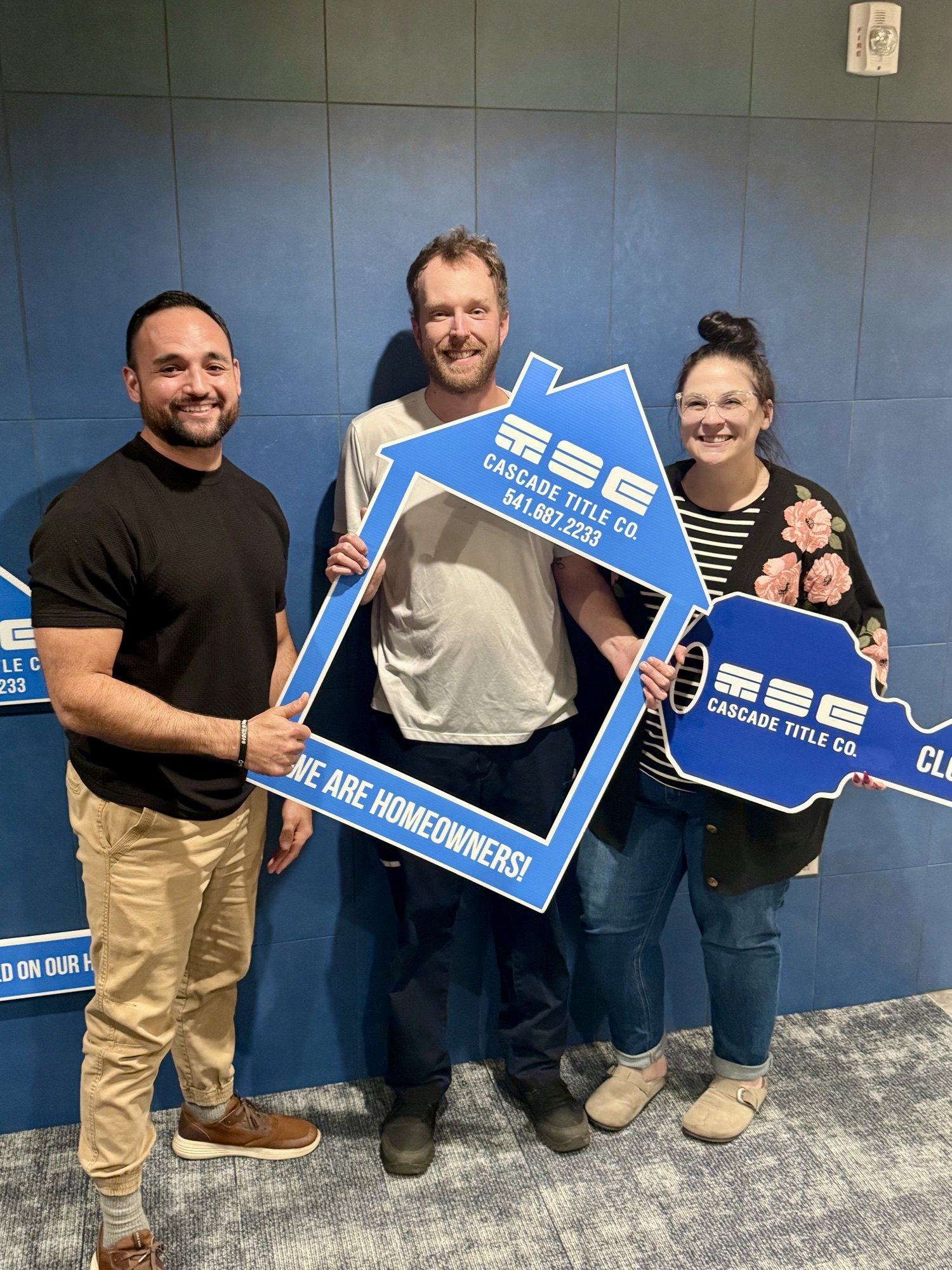 Brett Herring with new homeowners holding a Cascade Title sign